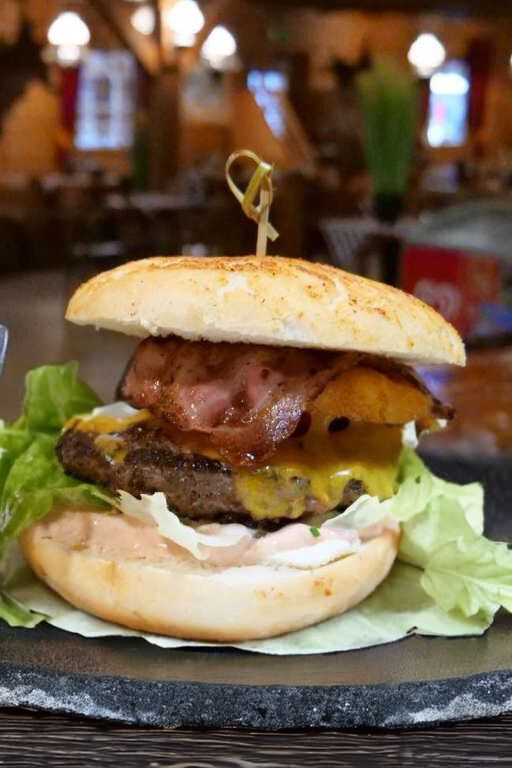 Saftiger Burger mit Rindfleisch-Patty, geschmolzenem Käse, knusprigem Bacon und frischem Salat im Steakhouse Zillertal.