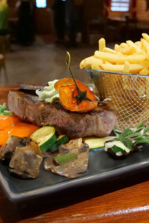 Saftiges Steak mit Kräuterbutter auf gebratenem Gemüse, serviert mit knusprigen Pommes im besten Restaurant im Zillertal.